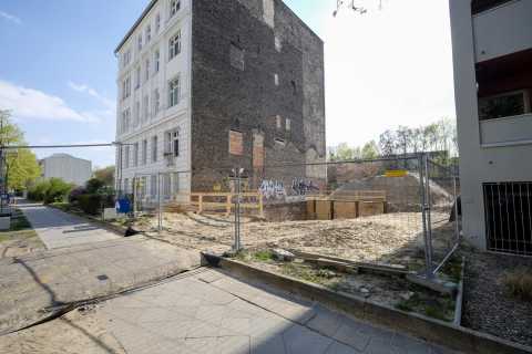 Eingezäunte Baustelle neben einem Altbau mit freistehender Brandwand.