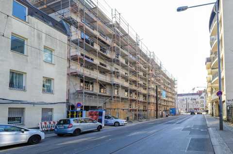Mehrstöckiges Gebäude mit Baugerüst an einer ruhigen Straßenkreuzung.