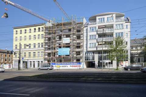 Wohnhaus im Bau mit Gerüst, Kran und umliegenden modernen Gebäuden.