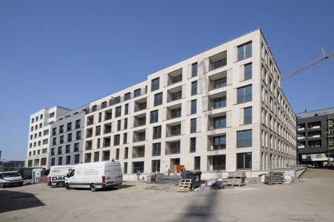 Neubau eines modernen, mehrstöckigen Wohnhauses mit Baustelle im Vordergrund.