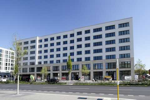 Modernes, mehrstöckiges Bürogebäude mit vielen Fenstern an einer Straße.