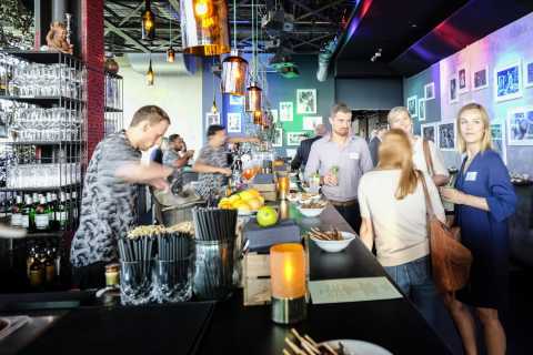 Barkeeper mischt Cocktails, Menschen unterhalten sich an einer modernen Bar.