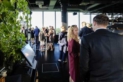 Menschen in Businesskleidung unterhalten sich bei einem Event in modernem Raum.