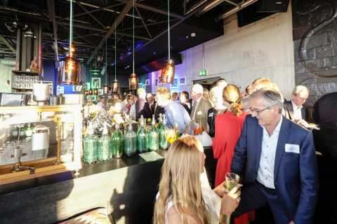 Viele Menschen unterhalten sich an einer Bar in einem stimmungsvollen Lokal.