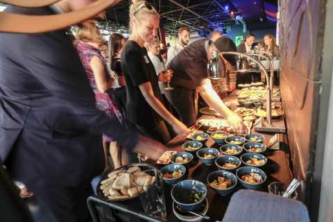 Menschen bedienen sich am Buffet mit vielen kleinen Schalen und Brot.