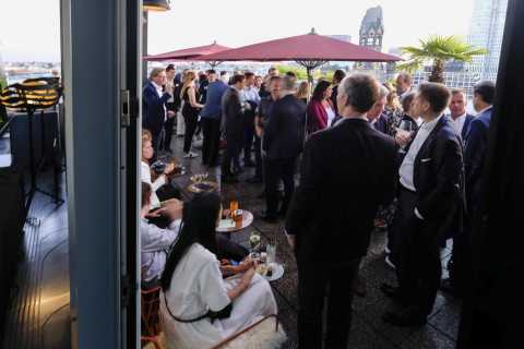 Menschen in Businesskleidung unterhalten sich auf einer Dachterrasse bei Event.