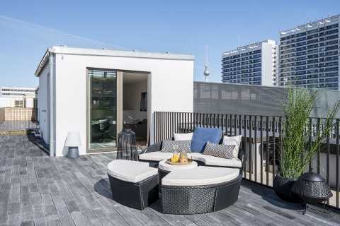Moderne Dachterrasse mit Sitzgruppe, Pflanzen und Blick auf Hochhäuser.