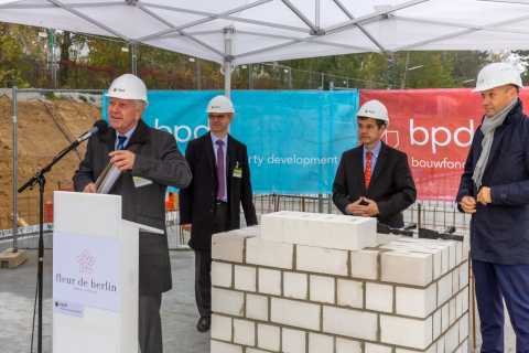 Vier Männer mit Bauhelmen bei einer Grundsteinlegung im Freien.